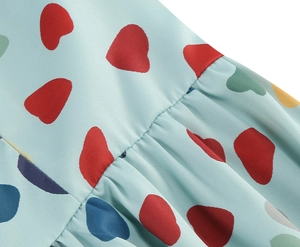 Detail of light blue pleated chiffon fabric with colorful heart print and fine stitching