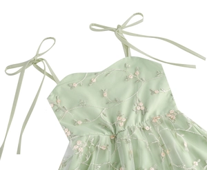 Détail de la robe en dentelle vert menthe avec broderie florale et nœuds aux épaules