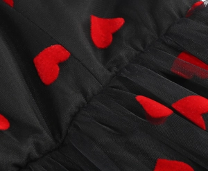 Detail of black tulle fabric featuring textured red heart embroidery and mesh layering