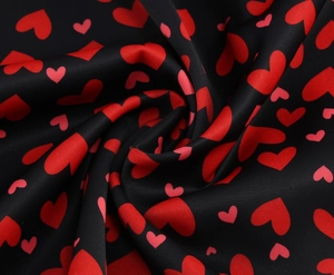 Détail du tissu noir avec motifs de cœurs rouges et texture satinée lisse