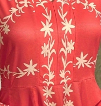 Dettaglio del ricamo floreale vintage su tessuto di abito rosso a maniche lunghe
