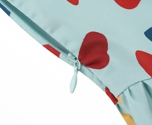 Close-up of heart print fabric featuring a light blue invisible zipper and detailed pleats