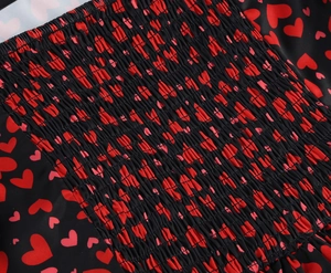 Détail d'imprimé cœur rouge sur tissu noir avec texture plissée smockée élastique