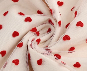 Dettaglio macro del tessuto a rete bianco con cuori rossi floccati per abiti eleganti
