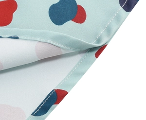 Detailed close-up of light blue fabric with colorful abstract print and neat hem stitching