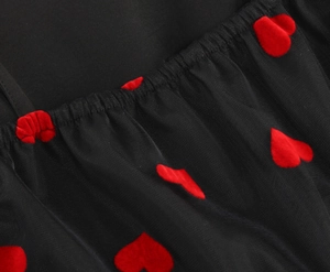 Detail of red heart embroidery and ruched mesh fabric on a black summer strap dress