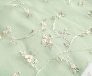 Gros plan du tissu en tulle vert menthe avec broderie florale et détails de pétales en 3D