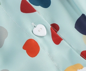Detailed macro view of heart-shaped white button on light blue shirt with heart print