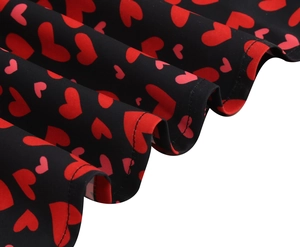 Détail de l'imprimé cœur sur robe noire à col carré montrant la texture plissée