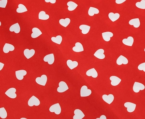 Close-up detail of red fabric with white heart pattern and smooth woven texture