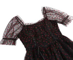 Dettaglio di abito in tulle nero con motivi a cuori rossi e raffinato fiocco in nastro