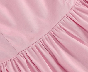Detail view of pink sleeveless cotton dress showing pleated waist and twill fabric texture