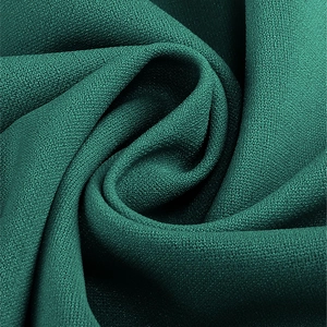 Gros plan sur le tissu en mousseline vert foncé montrant la texture et le drapé doux