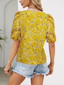 Close-up of bright yellow floral top showing back detail and elegant puff sleeves design