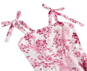 Detailed view of white floral dress featuring pink patterns and ribbon bow straps