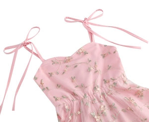 Détail de la robe rose en tulle avec broderie florale et bretelles à nœuds doux