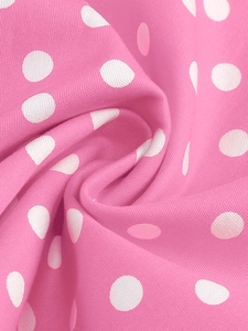 Détail macro du tissu rose à pois blancs montrant la texture douce et le drapé