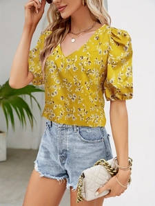 Detail view of yellow floral V-neck puff sleeve top paired with frayed denim shorts