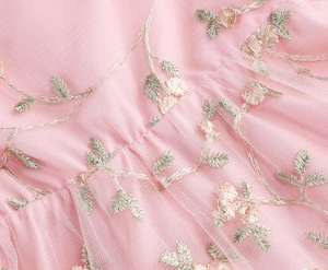 Détail macro du tissu en tulle rose avec broderie florale délicate et coutures de haute qualité