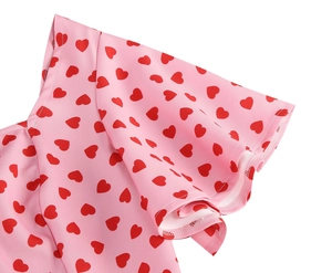 Detail of pink vintage dress showing red heart print and ruffled sleeve edges