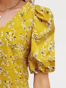 Close-up of a bright yellow floral blouse featuring a V-neckline and elastic puff sleeves