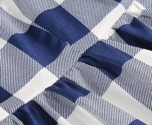 Dettaglio del vestito a quadretti blu e bianchi con cuciture precise e pieghe fitte