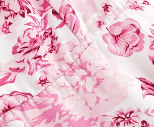 Macro shot of elegant pink floral print on white fabric showing detailed stitching and texture
