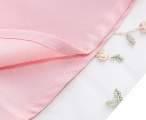Détail de la robe rose avec broderie florale délicate sur des couches de tulle blanc