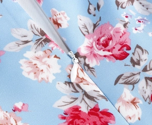 Close-up of invisible zipper detail on light blue floral cotton dress with rose patterns