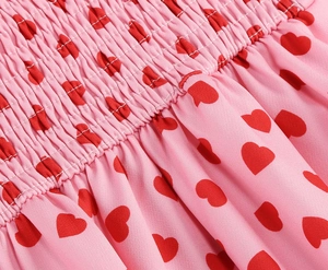 Macro shot of pink fabric featuring red heart prints and elastic smocking detail
