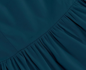 Close-up detail of dark blue cotton fabric showing fine twill texture and pleated design