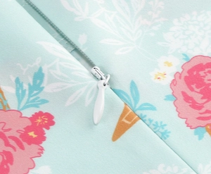 Detailed view of invisible white zipper on light blue floral girls dress textile