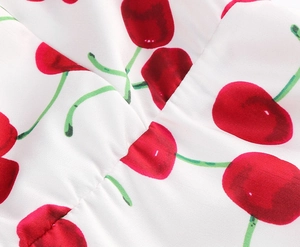 Close-up of floral print on white fabric featuring red cherry patterns and pleated details