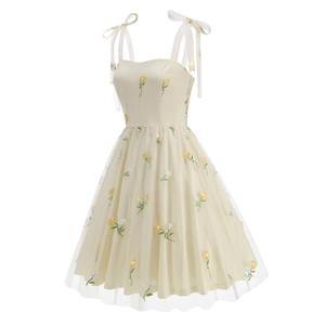 Detail of floral embroidery on a cream mesh dress with delicate ribbon shoulder straps