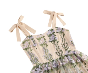 Detailed close-up of floral embroidery on apricot fabric with silk bow shoulder straps