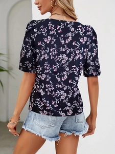 Back view of a casual short sleeve floral blouse paired with frayed denim shorts