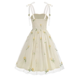 Close-up of yellow floral embroidery on delicate tulle mesh of a French style summer dress