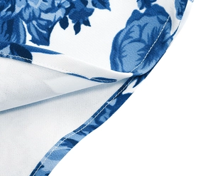 Detailed macro shot of fine stitching and blue floral pattern on white fabric dress