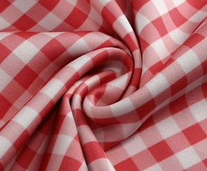 Detailed macro shot of red and white gingham fabric texture with soft pleats and folds