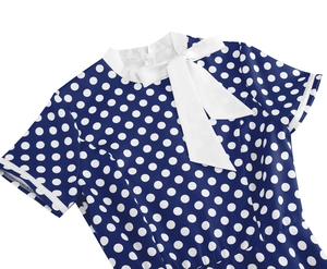 Détail de robe rétro à pois avec col Claudine blanc et élégant nœud papillon frontal