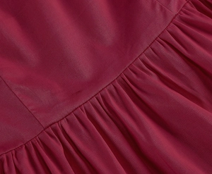 Macro shot of dark red sleeveless dress featuring fine twill texture and pleated waist seam
