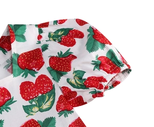 Detail of girls floral dress featuring puff sleeves and vibrant red strawberry prints