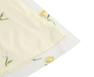 Macro shot of delicate daisy embroidery on a layered white mesh tulle maxi dress