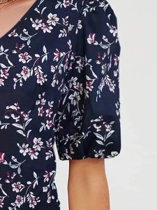 Detailed view of puff sleeves and floral print on a navy blue V-neck women's top