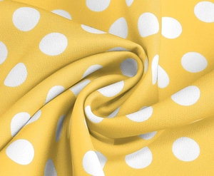 Macro shot of yellow fabric with white polka dots showing textile texture and drape