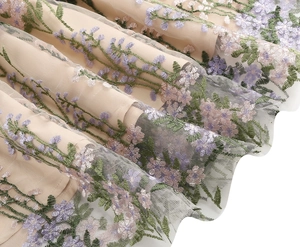 Close-up of floral embroidery on nude mesh fabric with pink and purple flower details