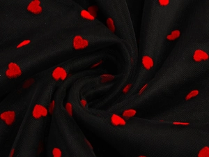 Detailed macro view of black mesh fabric featuring red flocked heart patterns on a skirt