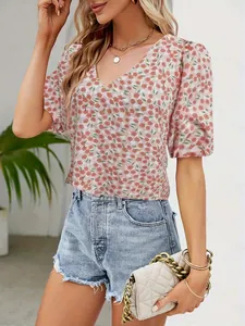 Detail of pink floral V-neck top with puff sleeves paired with denim shorts and white bag