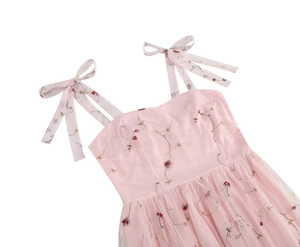Nahaufnahme von rosa Netz-Kleid mit roten Blumenstickereien und Schleifenträgern