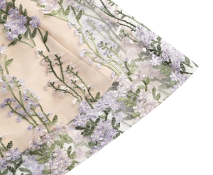 Detail of champagne dress with white mesh overlay and purple floral embroidery